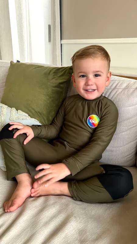 Tommy, 3 ans dans une combinaison "antidéshabillement" adaptée à son handicap et son hyposensibilité, conçue par sa maman.