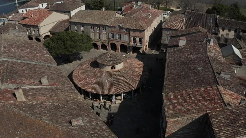 Une superbe halle aux grains circulaire trône sur une place pavée bordée de maisons à arcades.